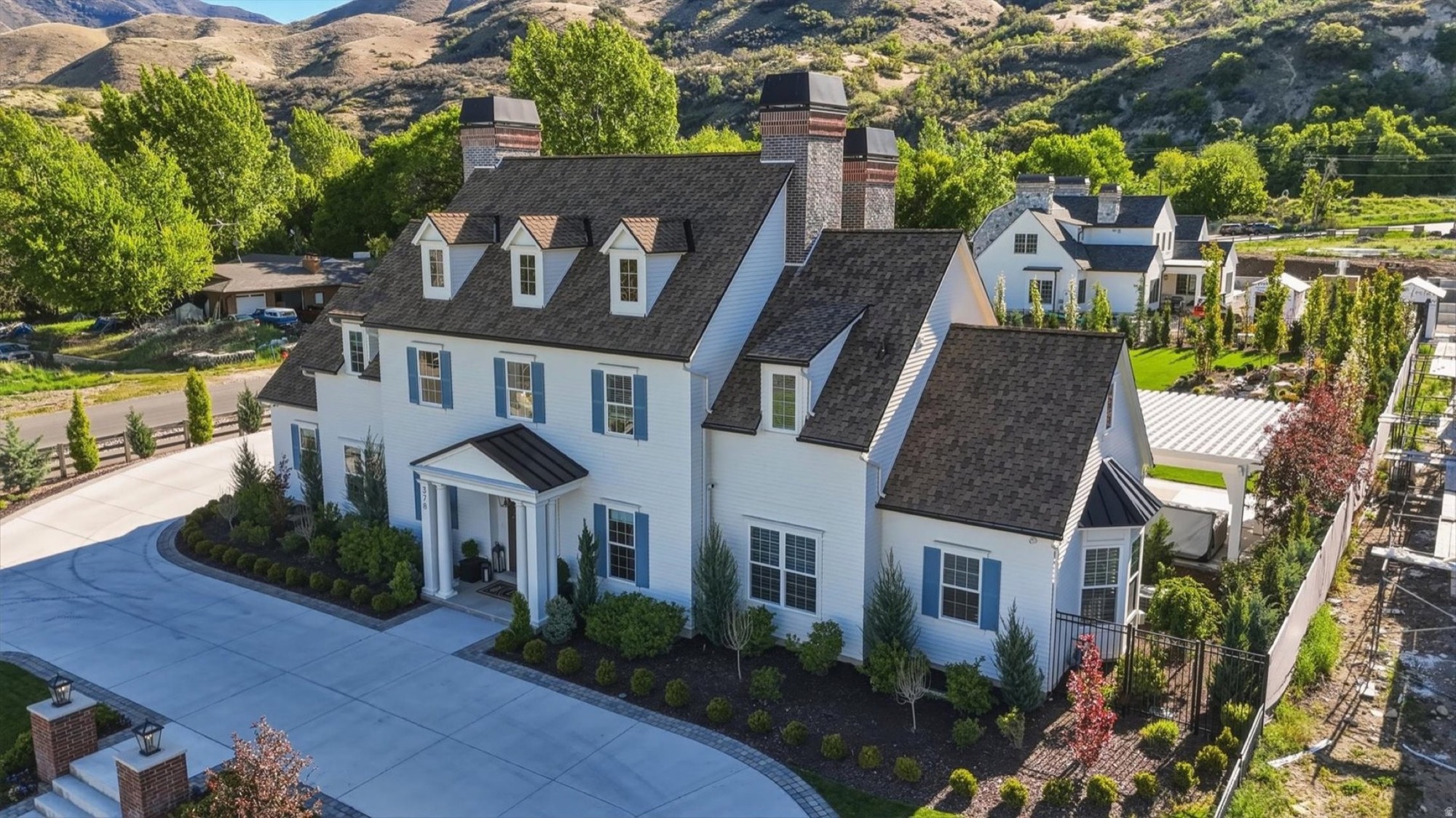 Aerial view of a white colonial home below the mountains in Mapleton, Utah